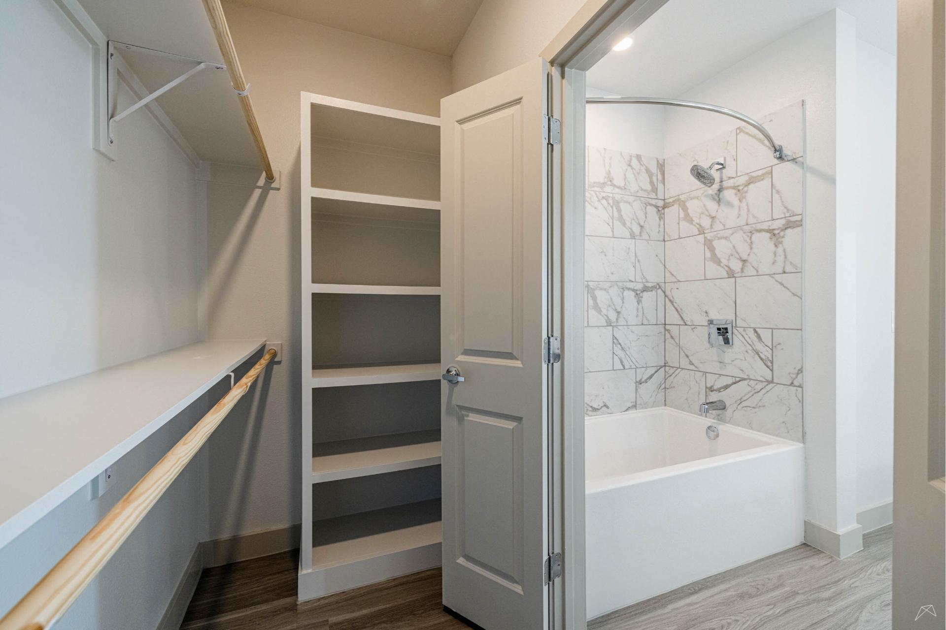 A bathroom with a bathtub and wood-look shelves.